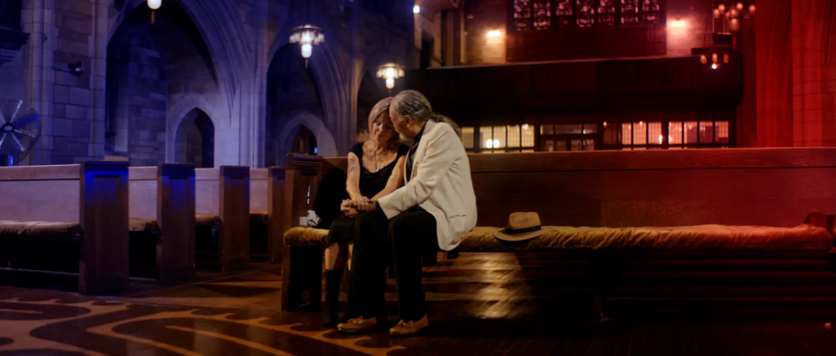 Cinematic production still of collaborators seated in a warmly lit interior